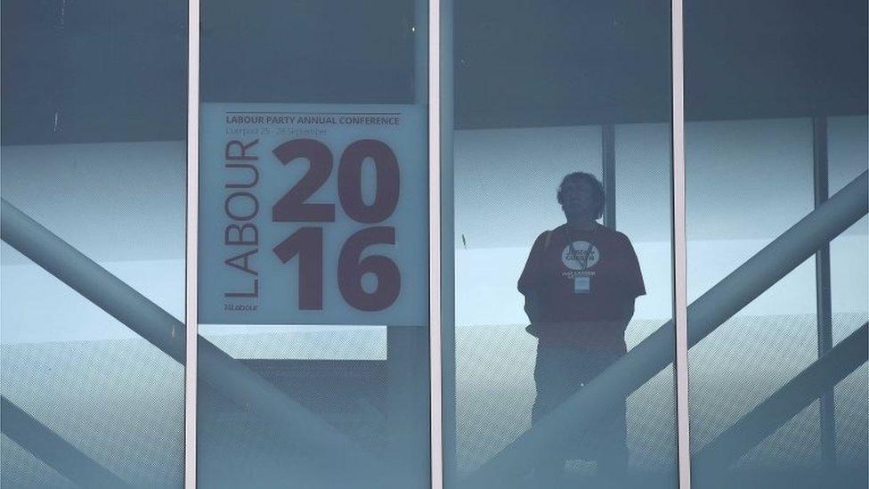 A Jeremy Corbyn supporter looks out of a window at Labour Party conference in Liverpool