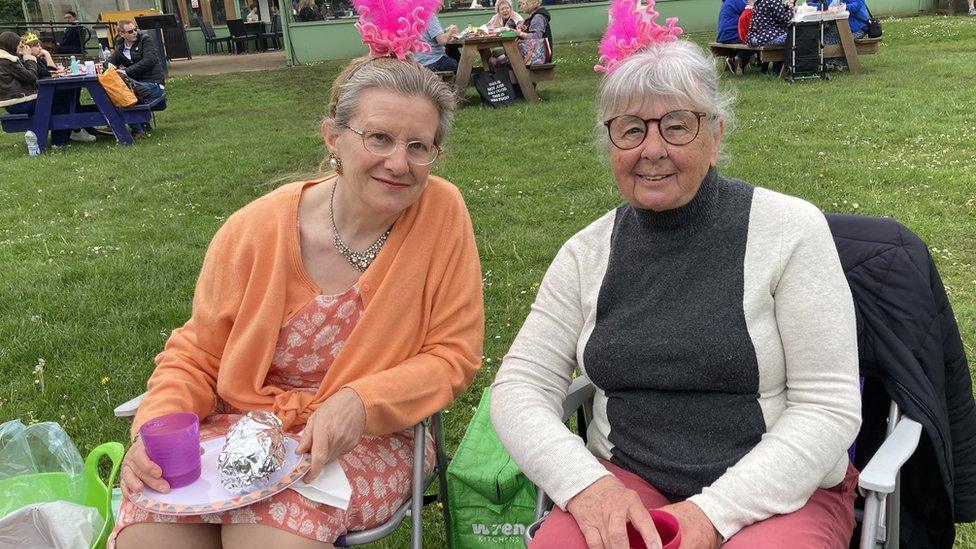 two women at a garden party with fancy hats