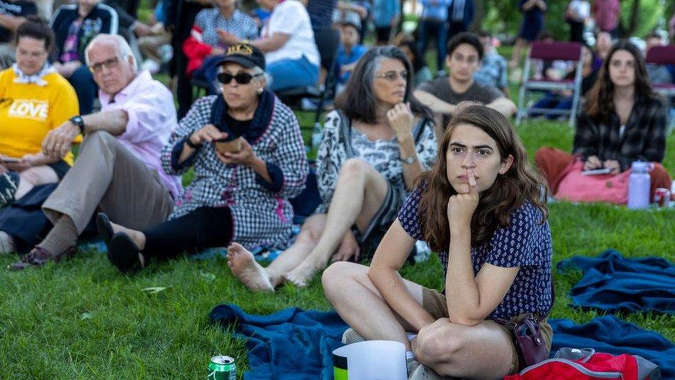 Washington DC residents watch the hearings in a public park