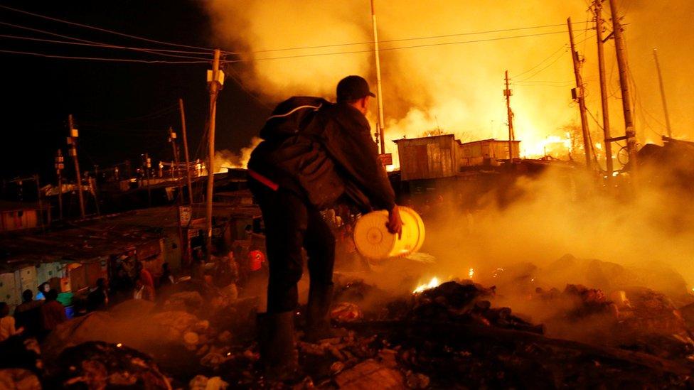 A resident attempts to extinguish a fire that broke out at the Kijiji slums in the Southlands estate of Nairobi, Kenya, January 28, 2018