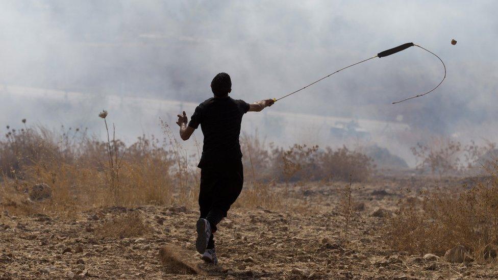 A Palestinian protester uses a slingshot to hurl a stone towards Israeli forces in the occupied West Bank (2 October 2105)