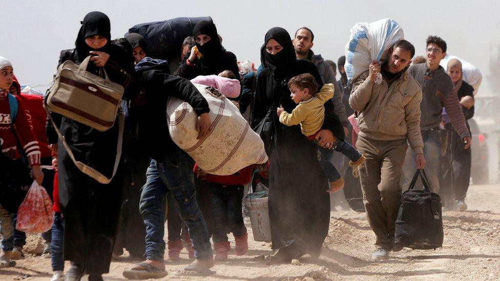 People walk with their belongings as they flee the rebel-held town of Hamouria, in the Eastern Ghouta, Syria (15 March 2018)