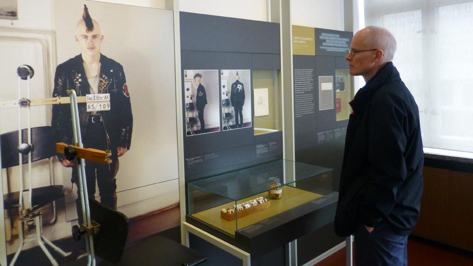 Chris Bowlby looks at police mugshots of a punk in the Stasi Museum