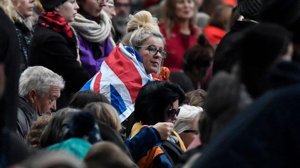 Crowd with woman in middle wearing Union Jack flag