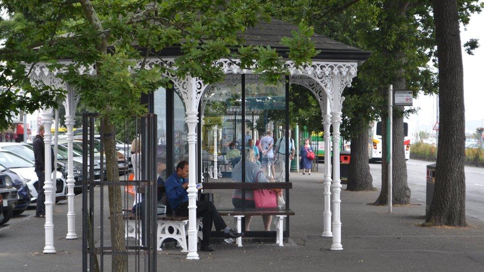 Guernsey's bus terminus in St Peter Port with people sat on benches