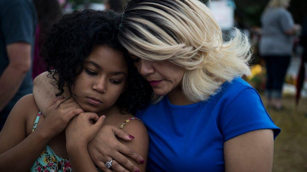 Tabitha and Jalaina embrace as dozens of people stand in the rain to pray and sing together at the memorial crosses near the Sutherland Springs First Baptist Church one week after 26 people were killed inside in Sutherland Springs, Texas on November 12, 2017