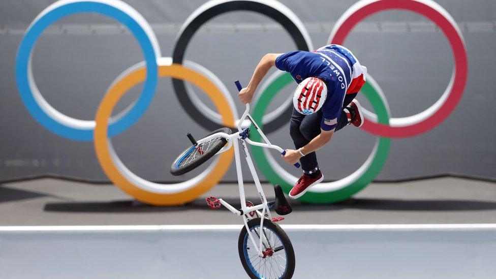 A BMC cyclist in front of the Olympics' sign