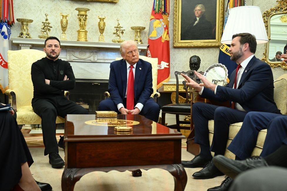 Zelensky, Trump and Vance sat in the Oval Office - Zelensky has his arms folded looking away while Vance has his arms outstretched.