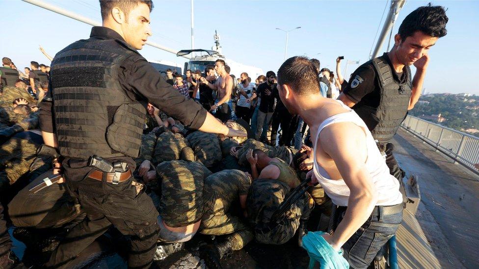 A policeman attempts to protect a group of soldiers