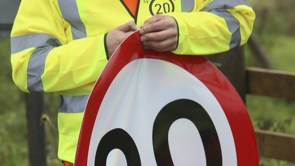 20mph stickers being applied to speed signs in the Scottish Borders