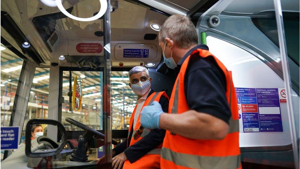 Sadiq Khan sits behind the wheel of a bus during a visit to a electric bus manufacturer