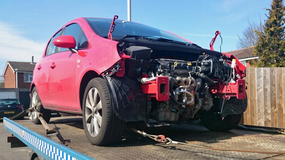 Red vandalised Vauxhall car on a flatbed truck