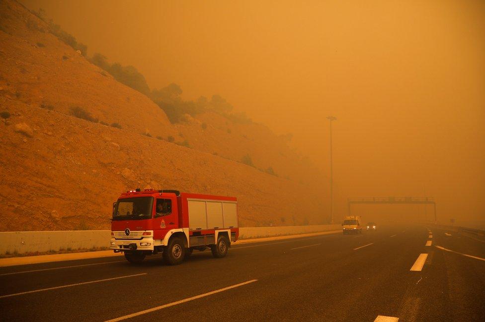 Firefighters are seen amid smoke as a wildfire burns in Kineta, near Athens