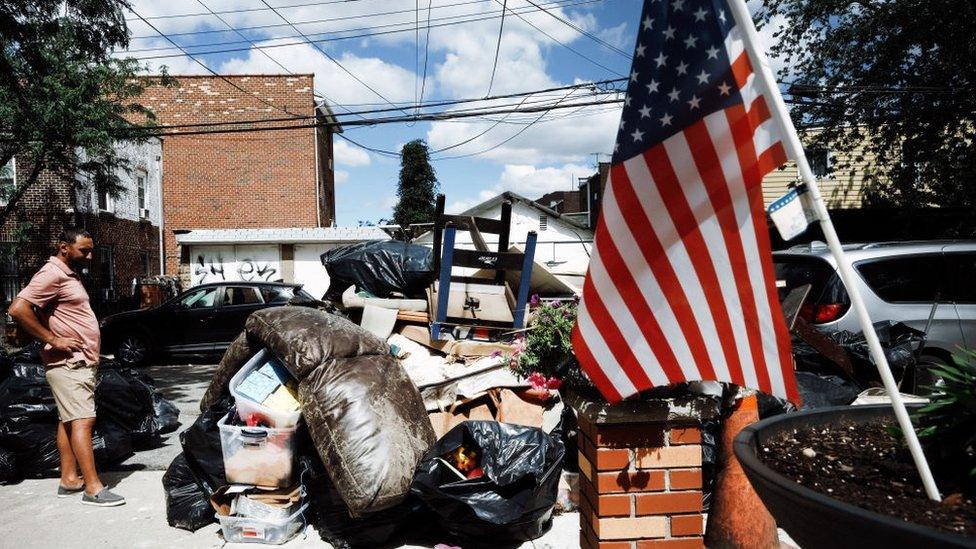 A person sorts through belongings from their flooded home in a Queens neighbourhood.