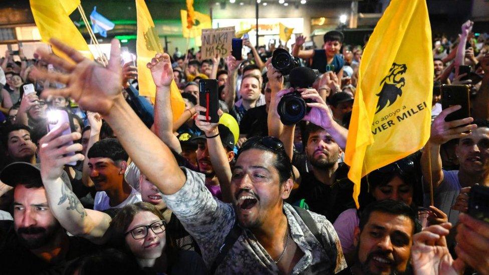 Supporters of Argentine presidential candidate for the La Libertad Avanza alliance Javier Milei celebrate after polls closed during the presidential election runoff outside the party headquarters in Buenos Aires on November 19, 2023.