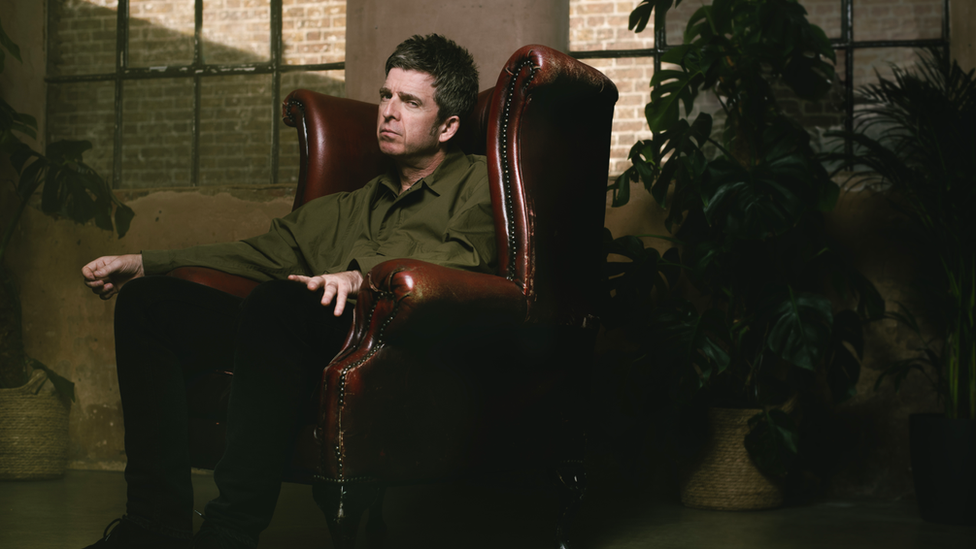 Noel Gallagher sat in a leather chair