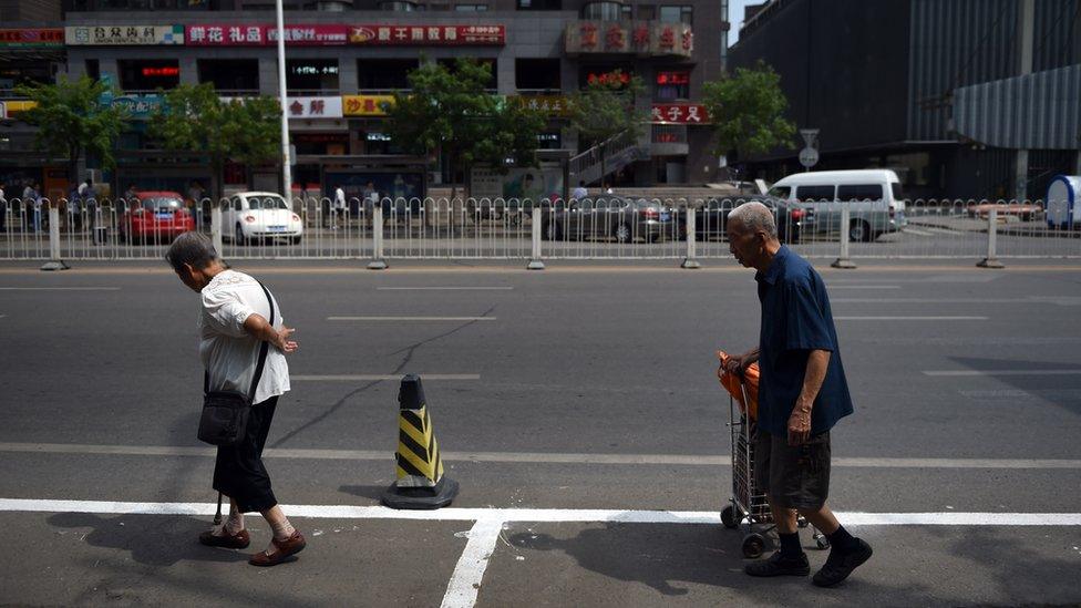 An elderly couple walk along a street in Beijing on June 17, 2015.
