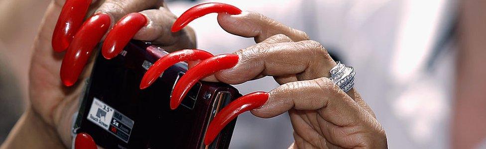 Woman with long fingernails holds a camera