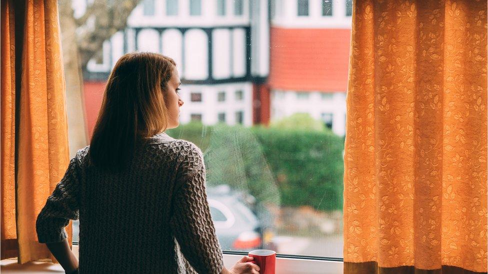 Woman staying home for safety during coronavirus pandemic and observing empty city