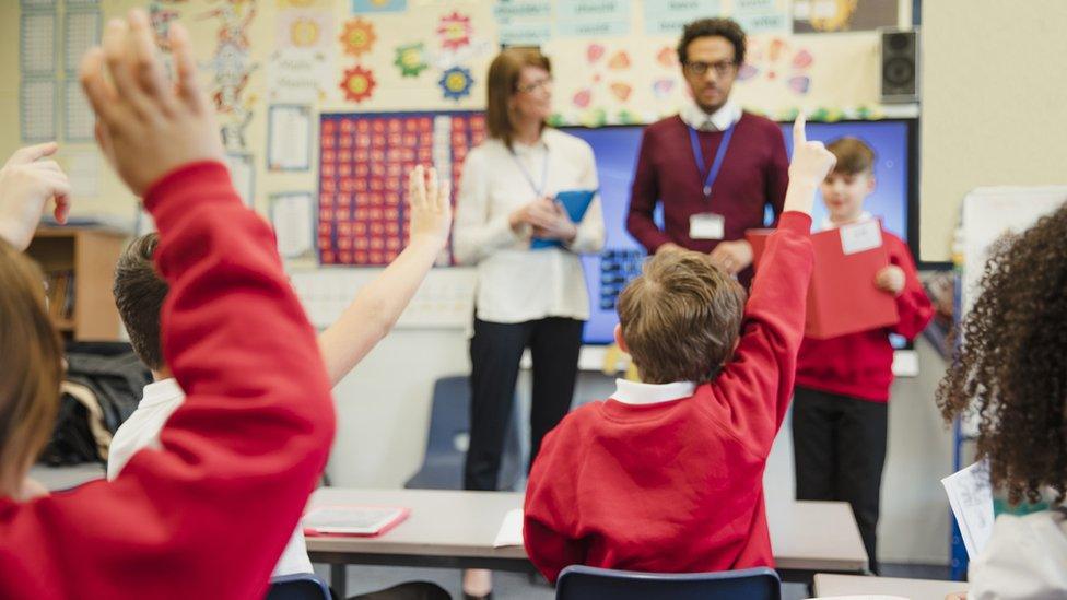 Primary school students raise their hands in class