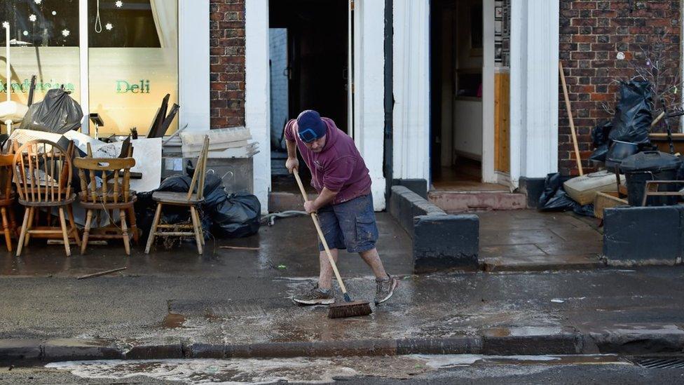 Man sweeps water out of home