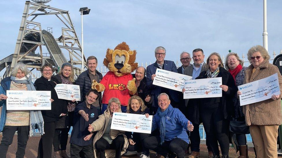 A group of people holding cheques outside Great Yarmouth Pleasure Beach