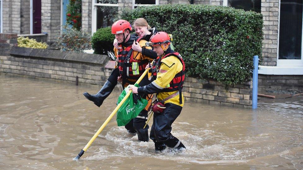 Woman being given a piggyback by rescue workers