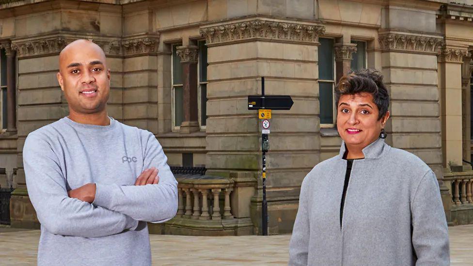 Zak Mensah and Sara Wajid stand outside Birmingham Art Gallery and Museum. Both are wearing grey jumpers.