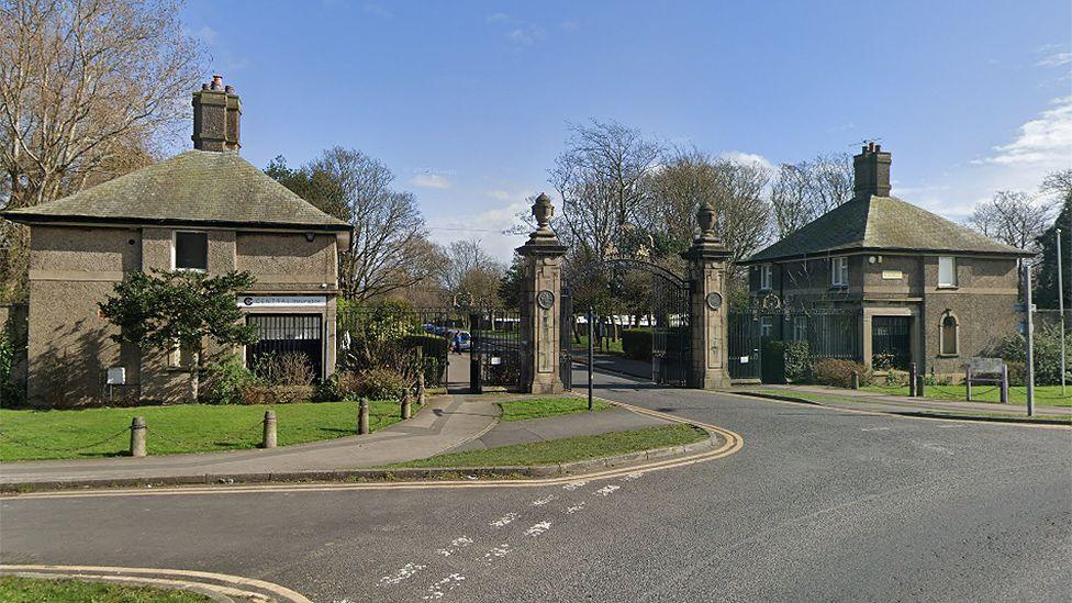 The entrance to Stanley Park, showing a gated entrance with two stone gatehouses on either side.
