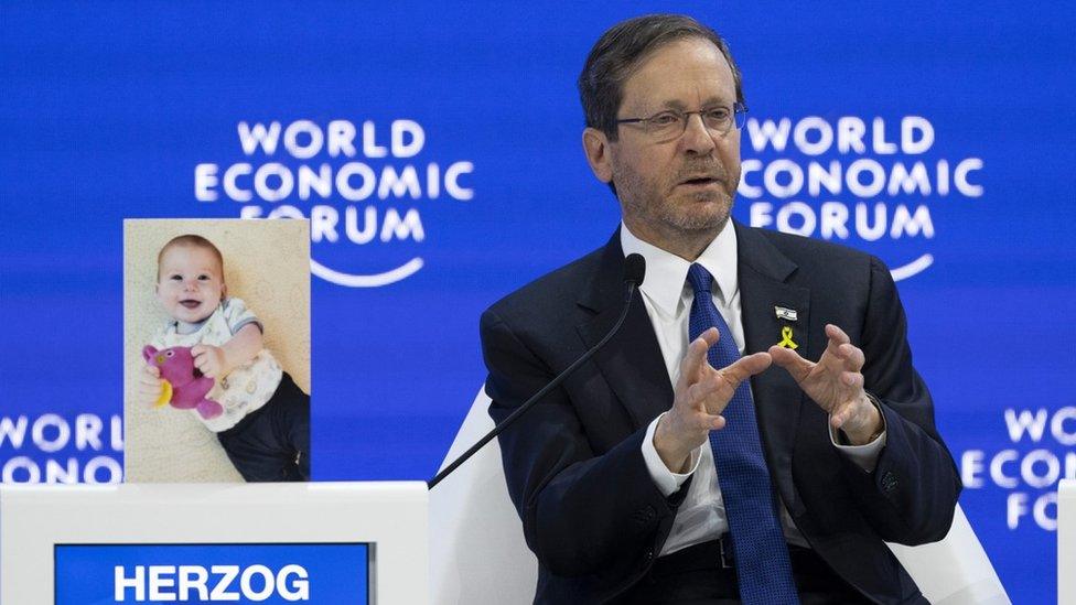 Israeli President Isaac Herzog speaks next to a photograph of infant Israeli hostage Kfir Bibas, at the World Economic Forum in Davos (18 January 2024)