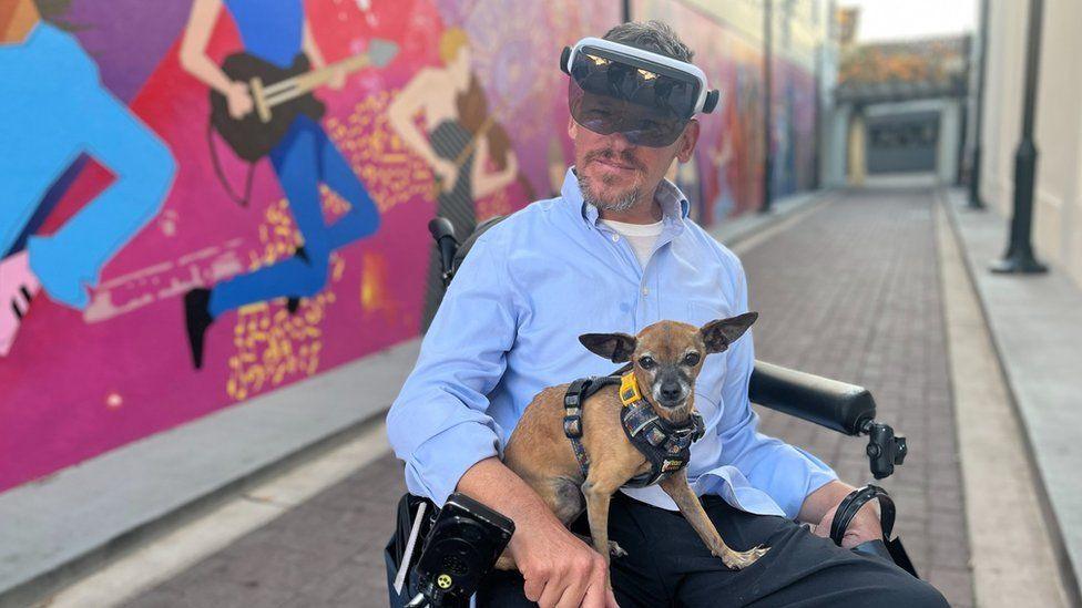 Chris wearing the visor while out on his wheelchair with his dog on his lap