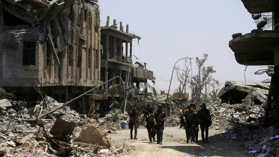 Iraqi security forces walk between destroyed buildings in the Old City of Mosul, Iraq (10 July 2017)