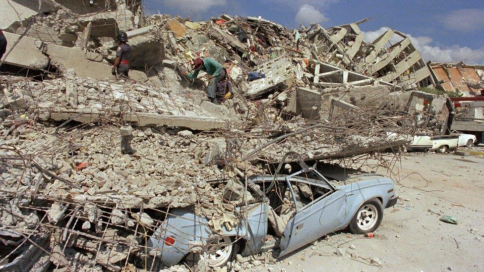 at least two buildings' worth of rubble with a car poking out