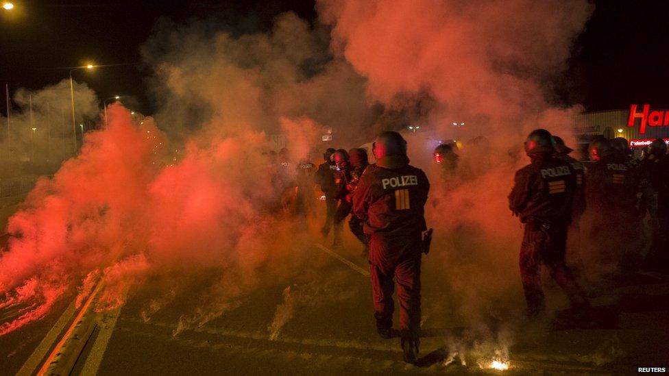 Police walk between flares thrown by right-wing protesters who are against bringing asylum seekers to an accommodation facility in Heidenau, Germany (August 22, 2015)