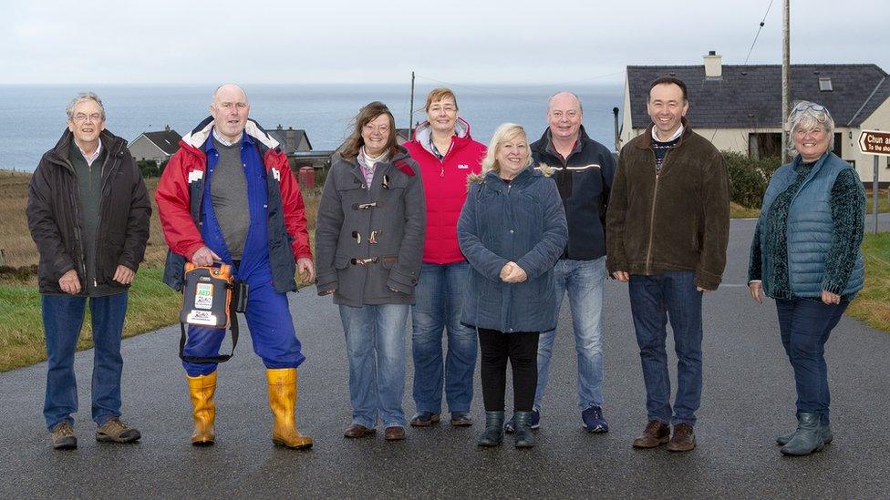 Muinntir a' bhaile a tha air an trèanadh air defibrillator.