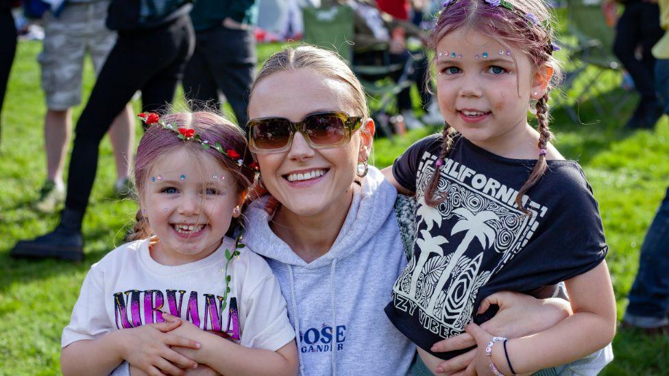 A young woman with her arms around two young girls at the festival last year