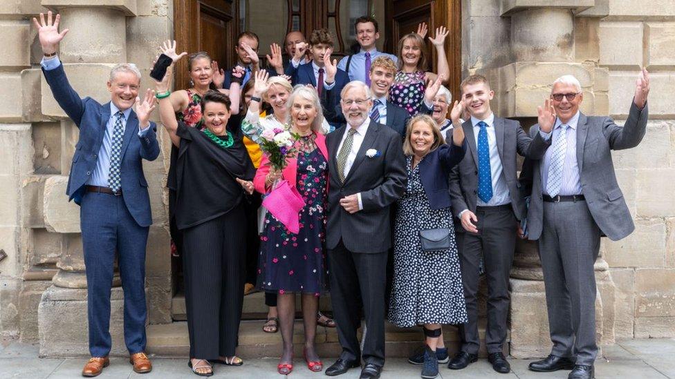 A group of people celebrating on the steps of the Guildhall