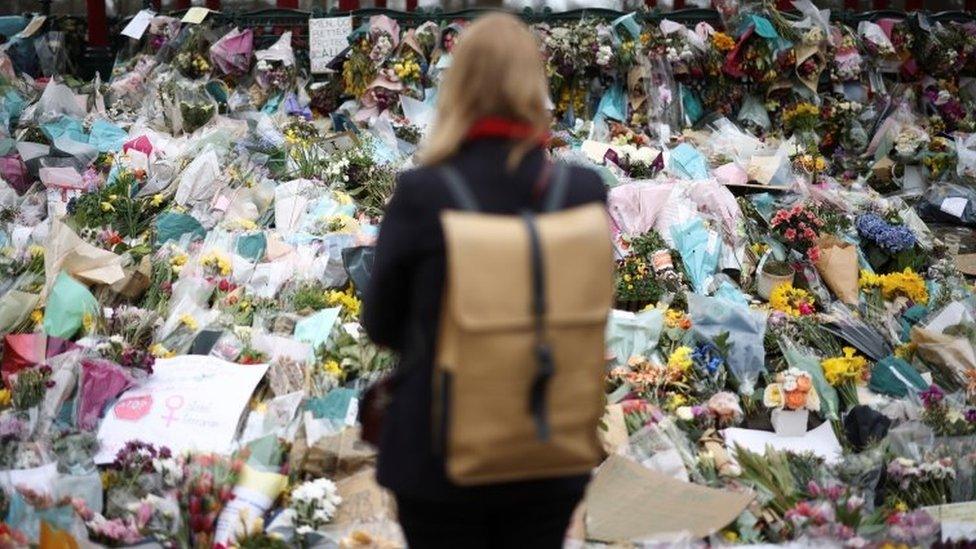 A woman looking at the flowers in Clapham Common left in memory of Sarah Everard