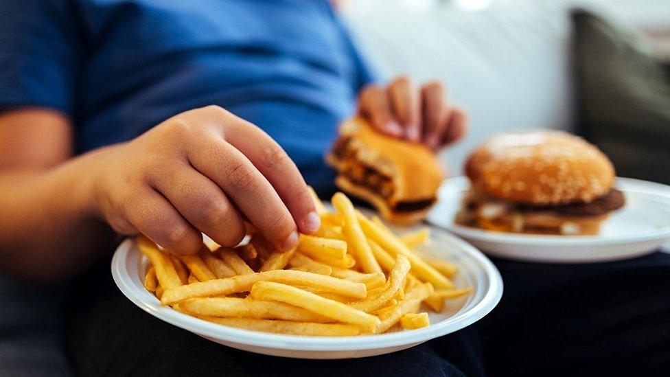 Anonymous child eating burger and chips at home