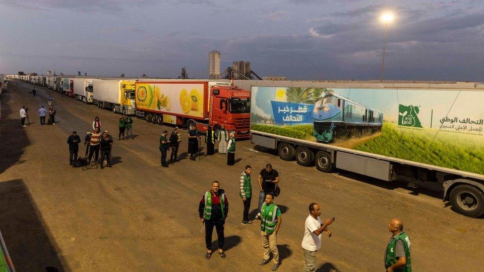 Aid convoy trucks wait on the Egyptian side of the Rafah crossing on 17 October