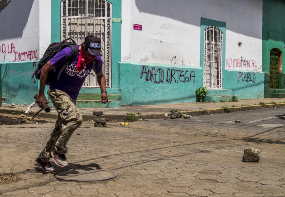 A protester carrying a home-made mortar runs to avoid police snipers in Masaya on 13 June 2018