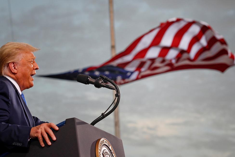 US President Donald Trump speaks, with a flag behind him, during a campaign rally at Cecil Airport in Jacksonville, Florida, on 24 September 2020