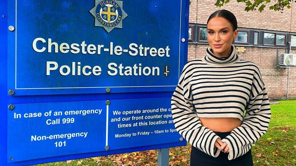 Vicky Pattison stands next to a police station sign