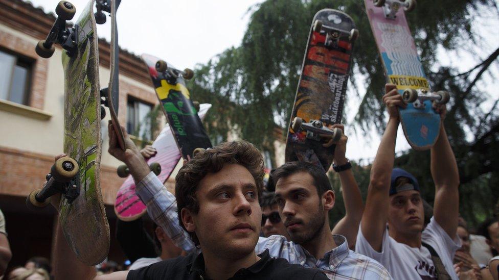 Fellow skateboarders paying tribute with their boards aloft