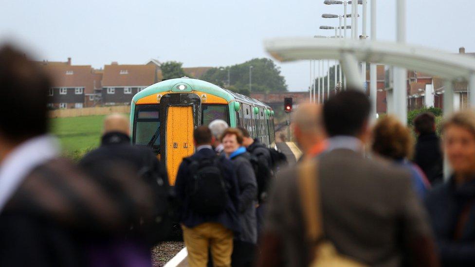 People standing on a train station platform with a train visible nearby