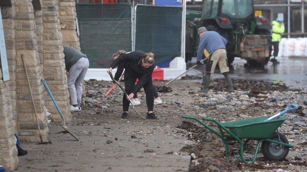 People cleaning up stones brought in by the sea