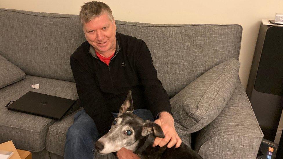 Philip Horner at home on his settee with a dog