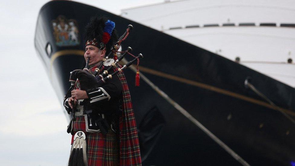 A piper plays next to The Royal Yacht Britannia in Edinburgh