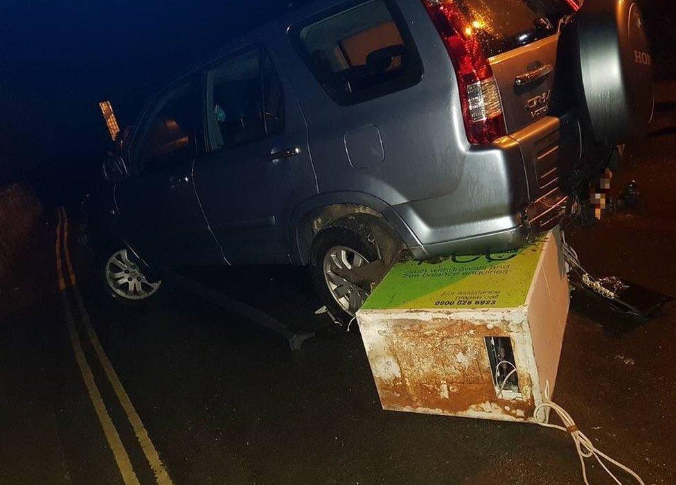 ATM wedged beneath parked car