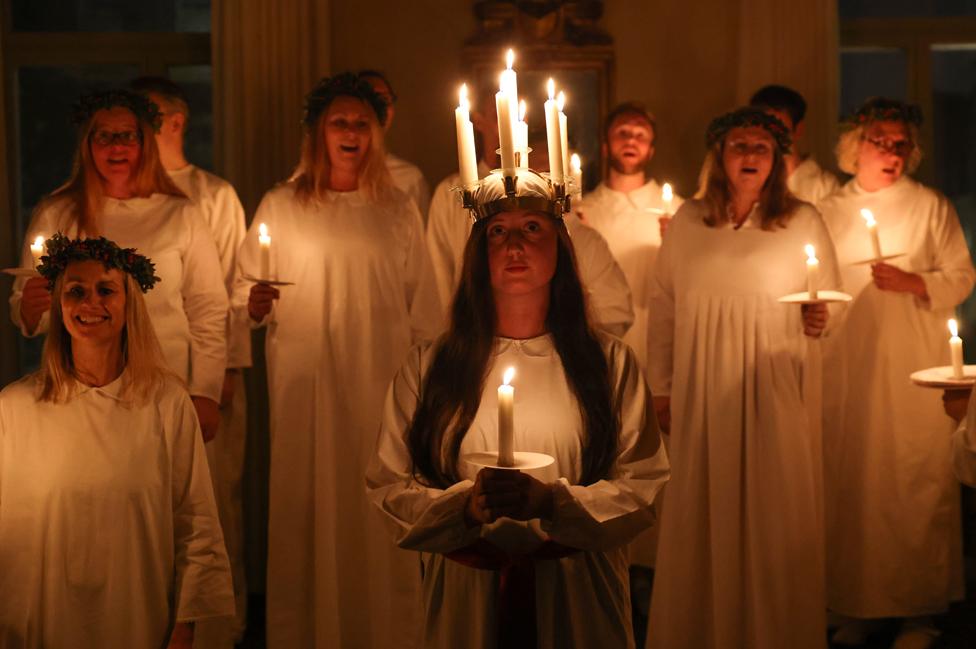 Members of the London Nordic Choir dressed in white and carrying candles lead a Lucia procession at the Swedish Ambassador's Residence on 5 December 2022.